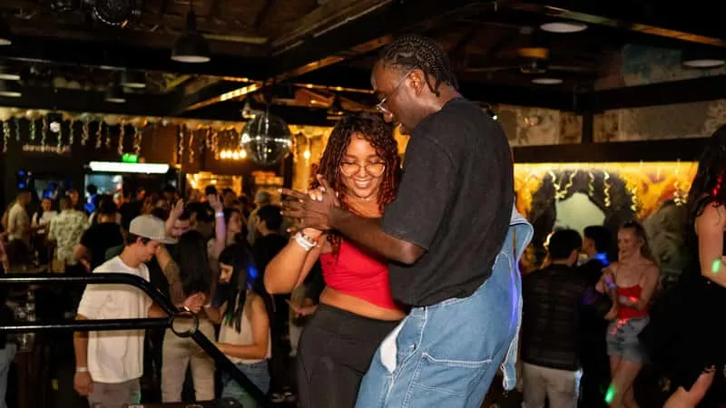 Tourists learning salsa dancing with a local instructor on a Medellin Colombia nightlife club tour in Provenza