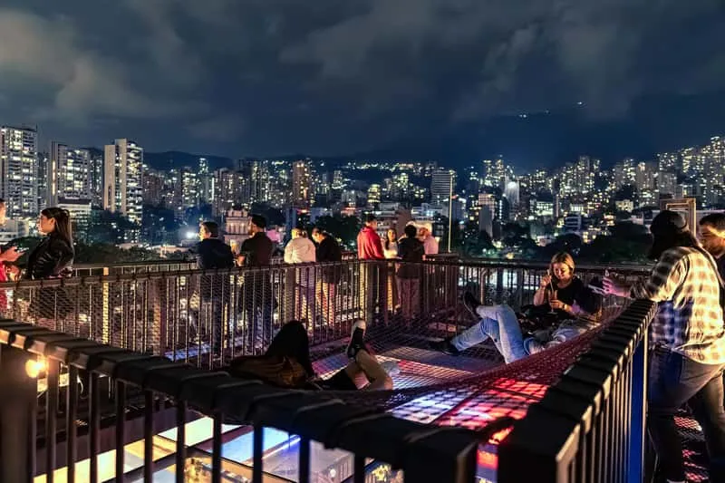Group enjoying drinks and dancing on a rooftop with El Poblado city views on a Medellin Colombia nightlife pub crawl